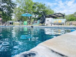 A tranquil pool area with a blue umbrella and chairs, showcasing the offerings of a commercial pool service